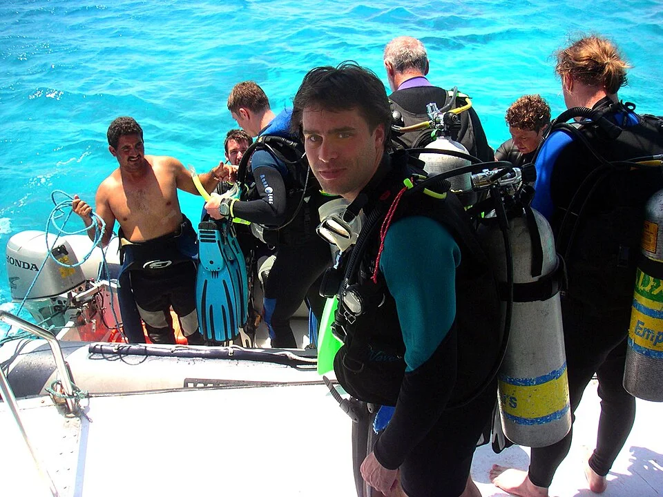 Divers on a Red Sea day boat prepare gear neatly with moored line attached, emphasizing safe entries and reef protection.