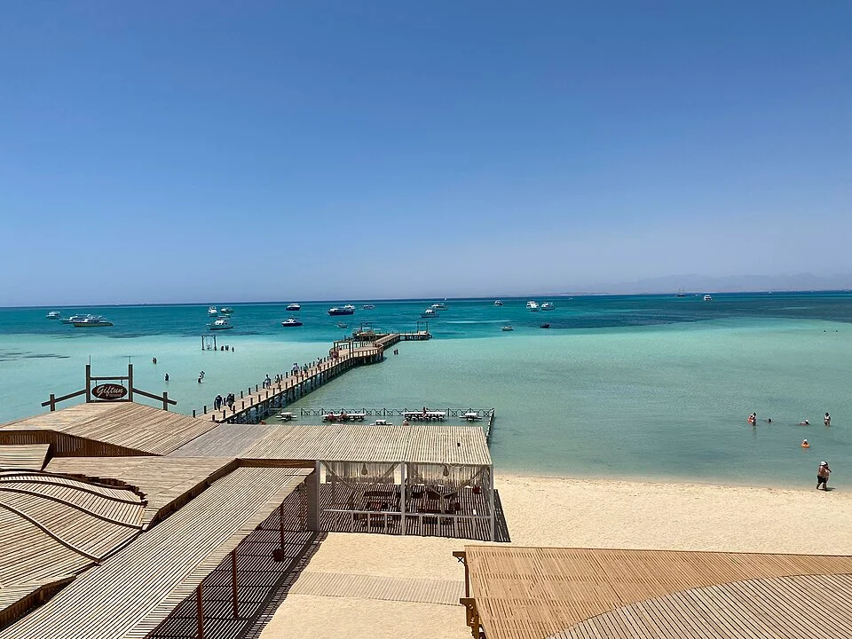 Powder-white sandbar and shallow turquoise lagoon at Orange Bay with day boats moored on a calm morning near Hurghada.