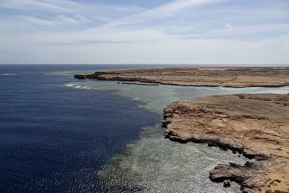 Snorkelers drift above a vibrant Ras Mohammed reef slope with clear 25-meter visibility and soft spring sunshine.