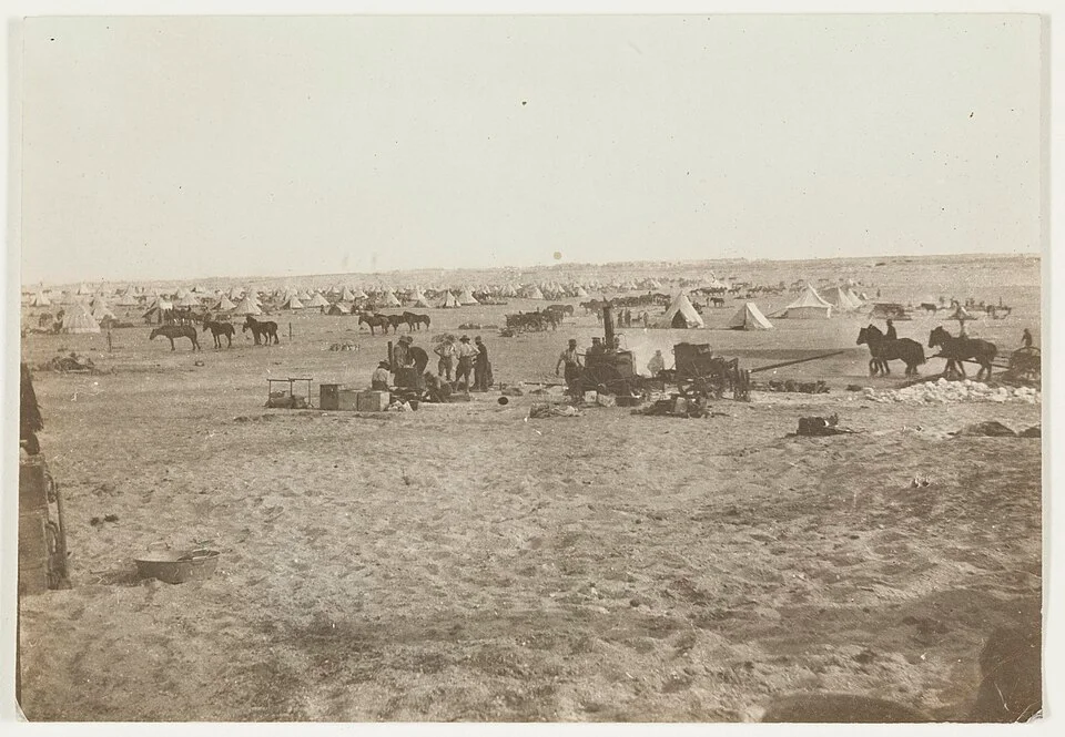 A small Bedouin-style camp set among tawny Sinai dunes at dusk with a tea kettle resting near the fire.