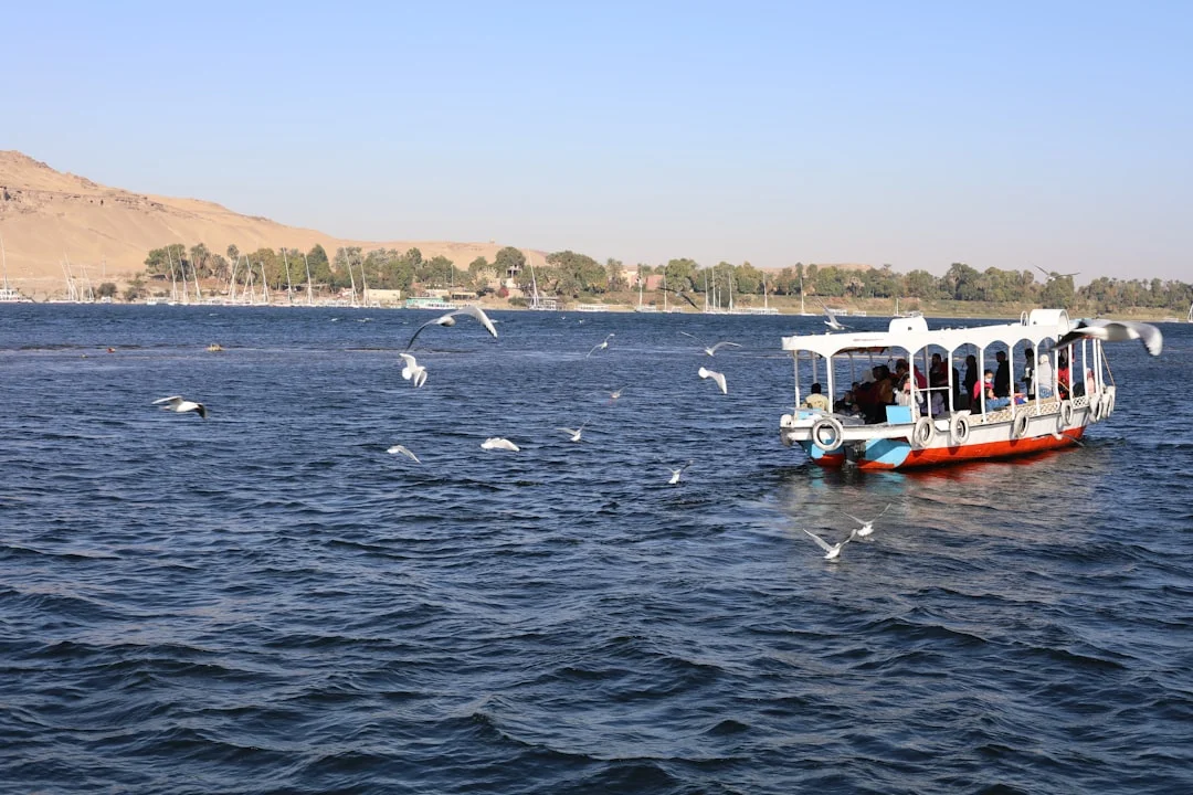 Glass‑bottom style boat cruising over turquoise water in Dahab with tourists looking down at the reef.