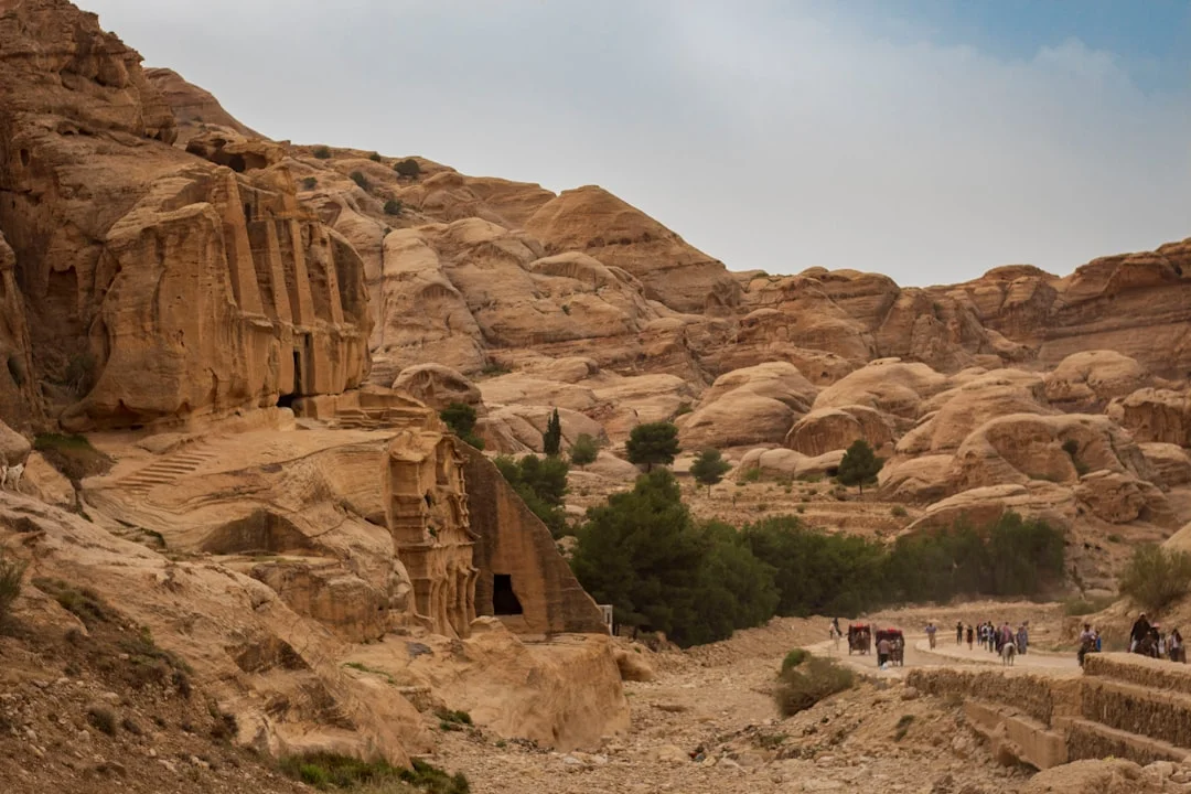 Des visiteurs s'approchent de l'entrée d'un tombeau rupestre dans la Vallée des Rois, tandis que les falaises s'illuminent au petit matin.