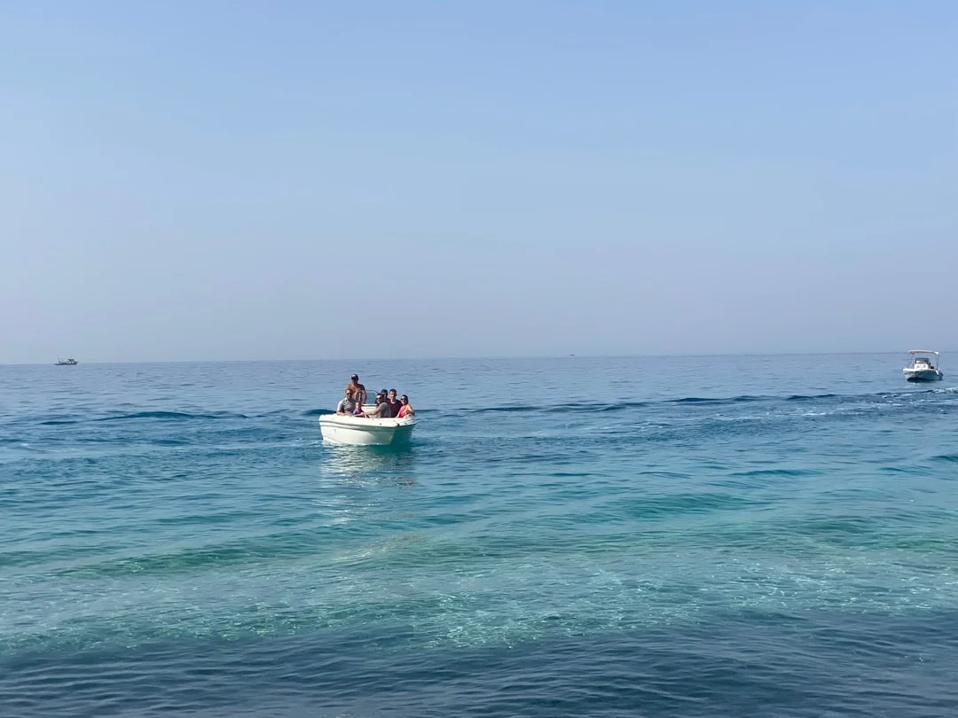 Snorkelers finning along Dahab’s Blue Hole outer reef ledge with cobalt drop-off and sunbeams
