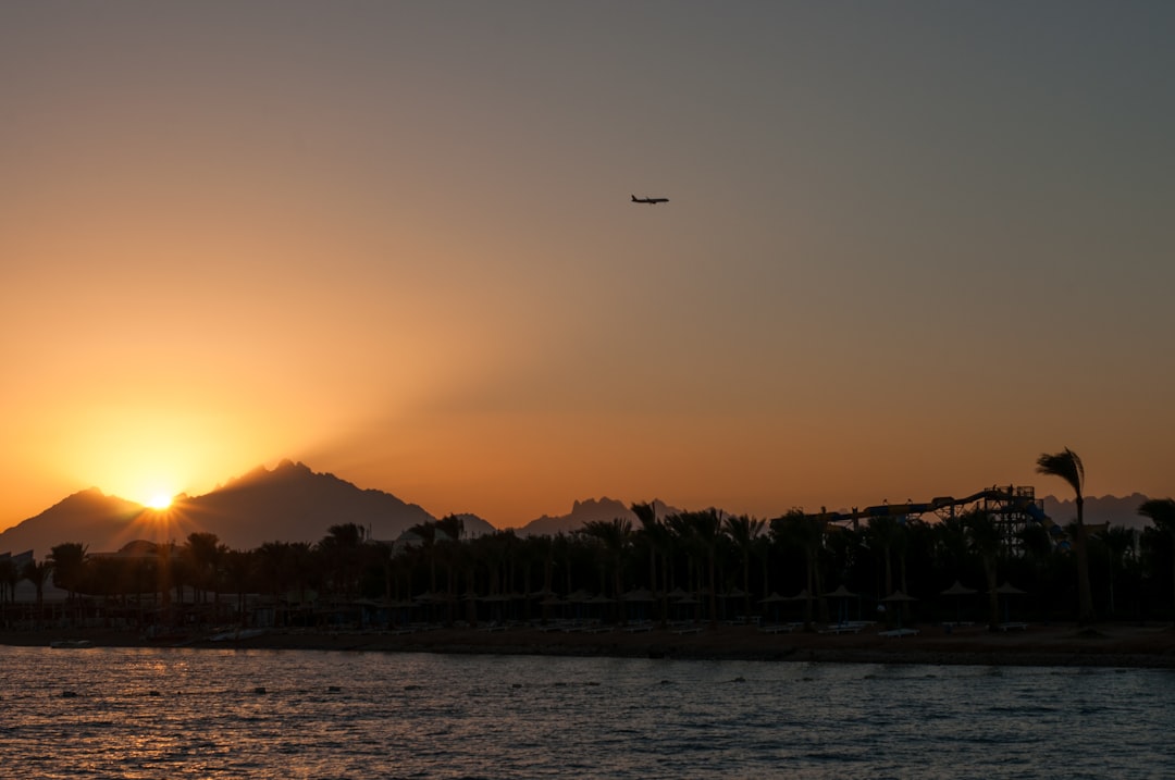 Aerial view of Hurghada’s coastline at sunset with marinas, sandy beaches, and turquoise shoals glowing under orange light